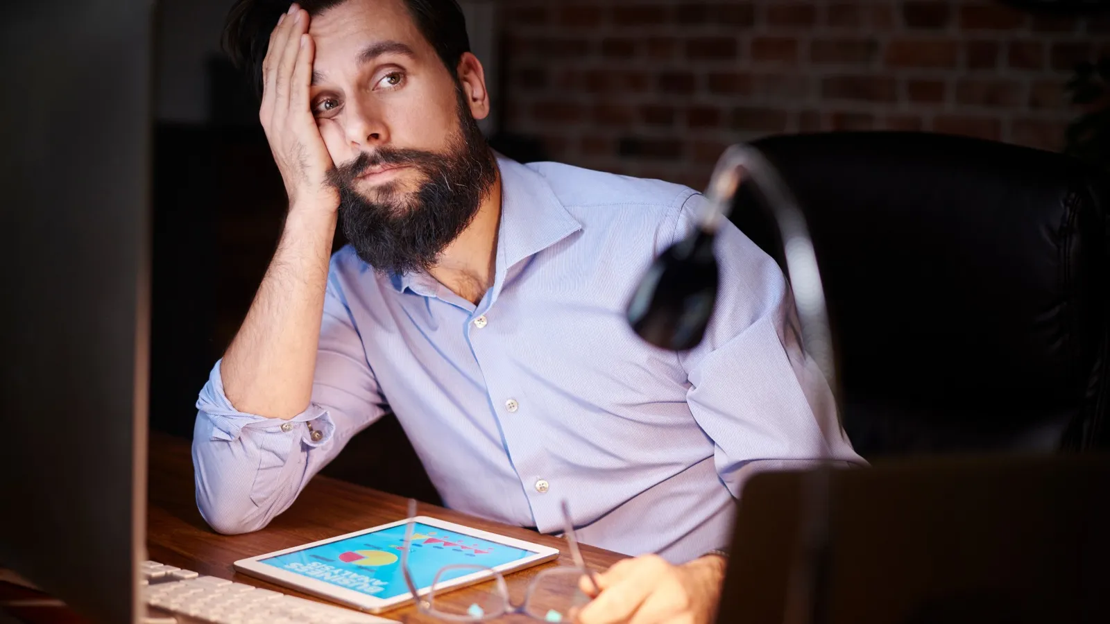Tired looking employee in font of monitors.