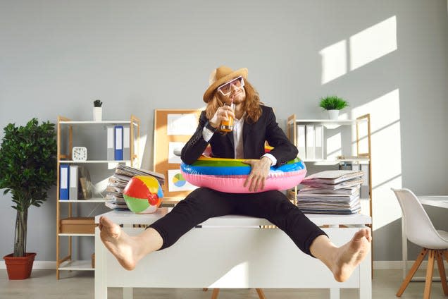 Man wearing pool tube, drinking on top of a office desk.